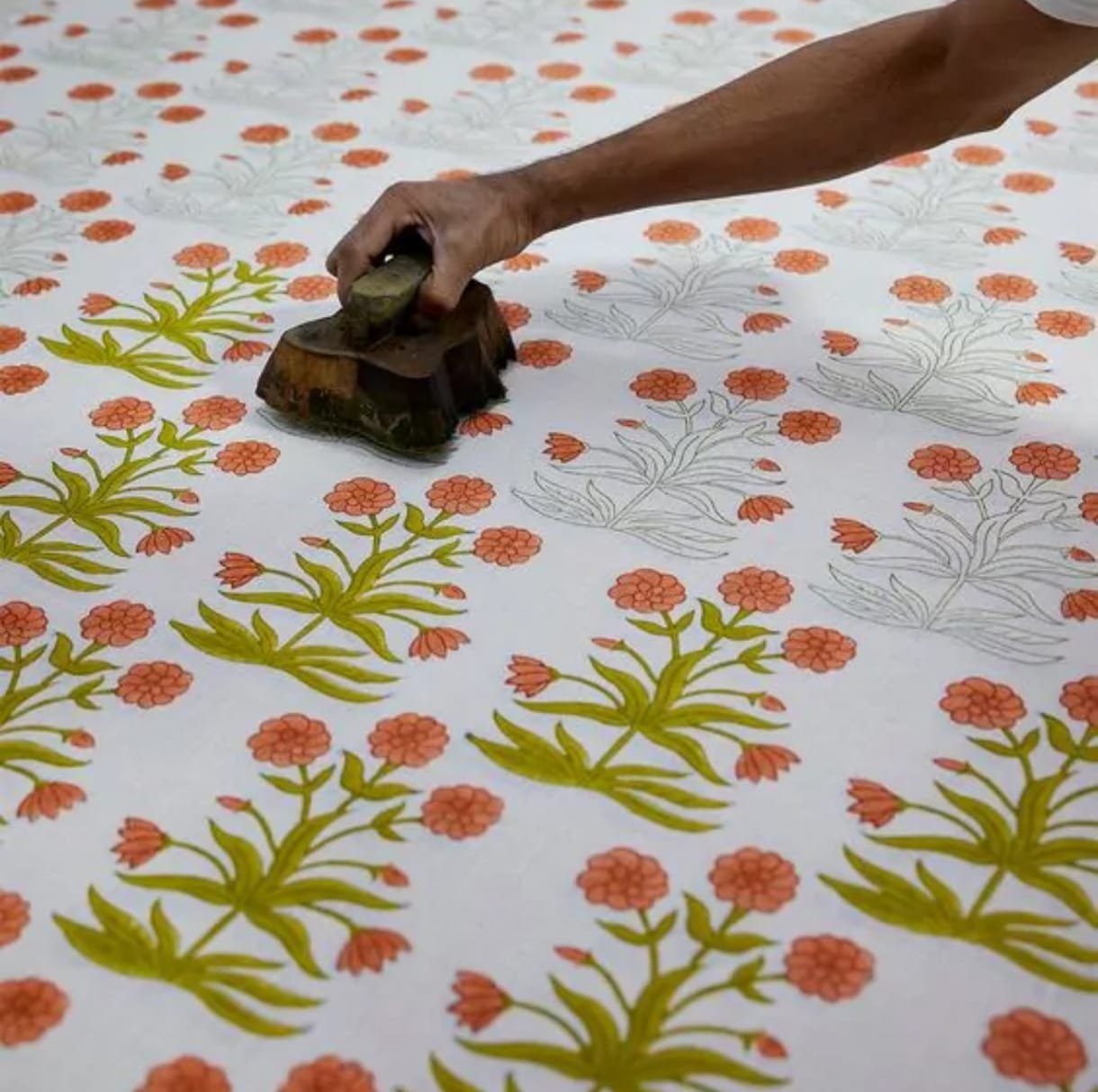 Artisan hand block-printing a marigold pattern on fabric