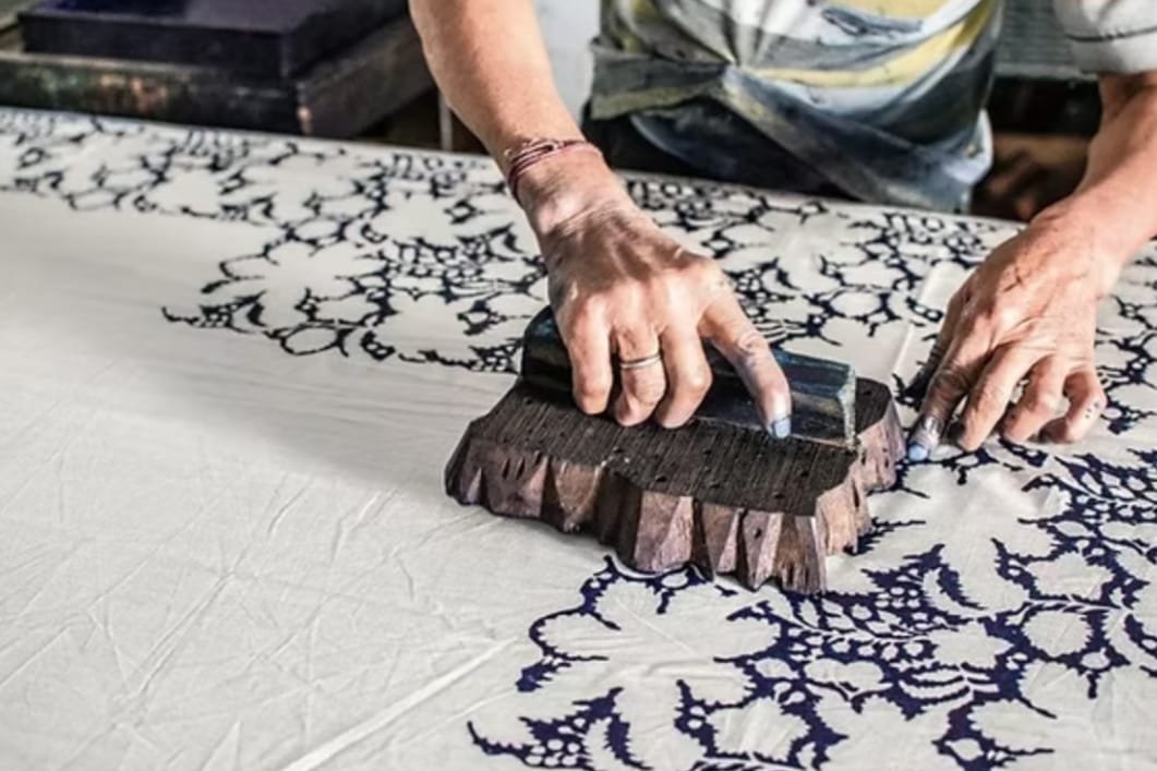 Artisan hand block-printing a navy floral pattern on fabric