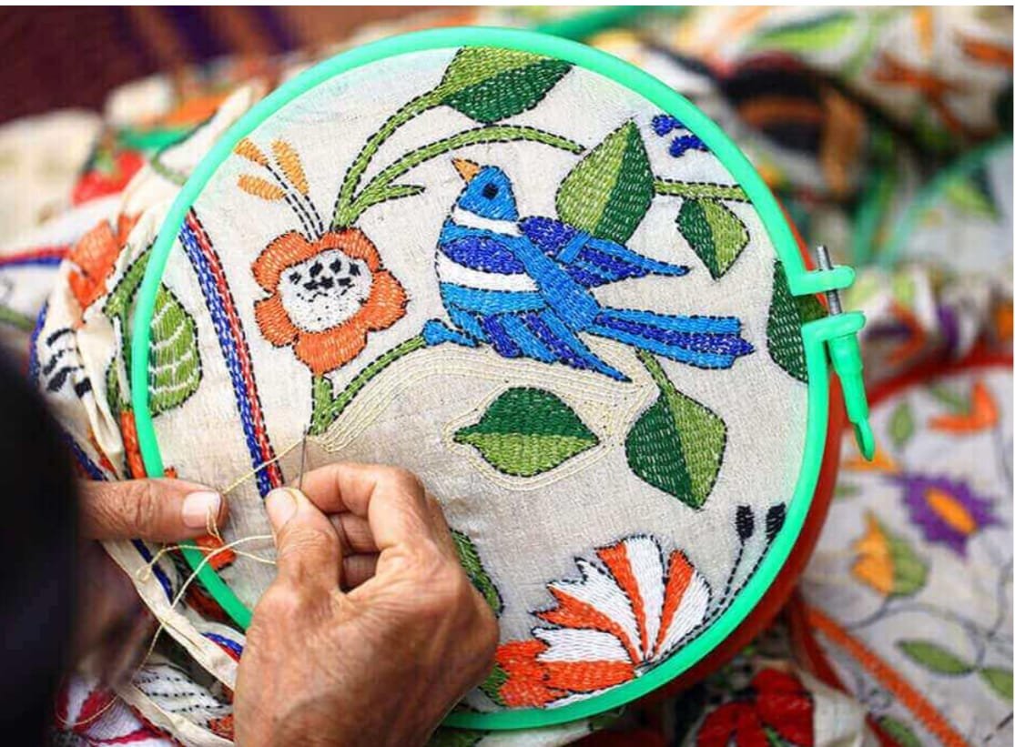 Artisan hand-embroidering a bird motif
